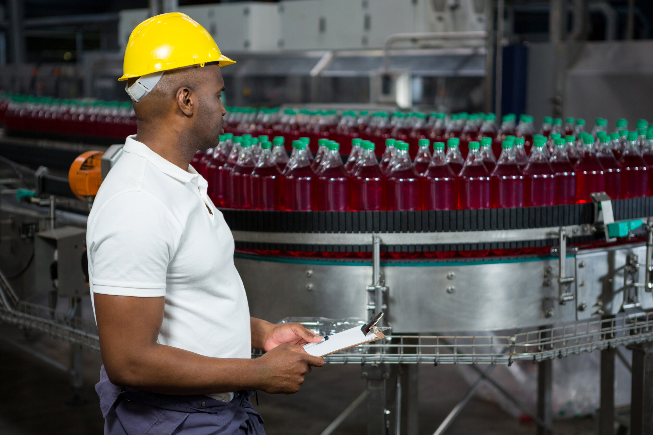 Side view of male worker inspecting bottles in juice factory